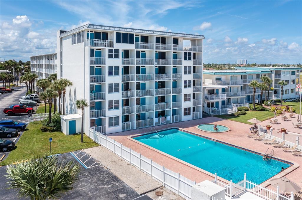 An exterior view of a multi-story apartment building with a swimming pool and parking lot — 935 S ATLANTIC AVENUE UNIT 303, DAYTONA BEACH, FL