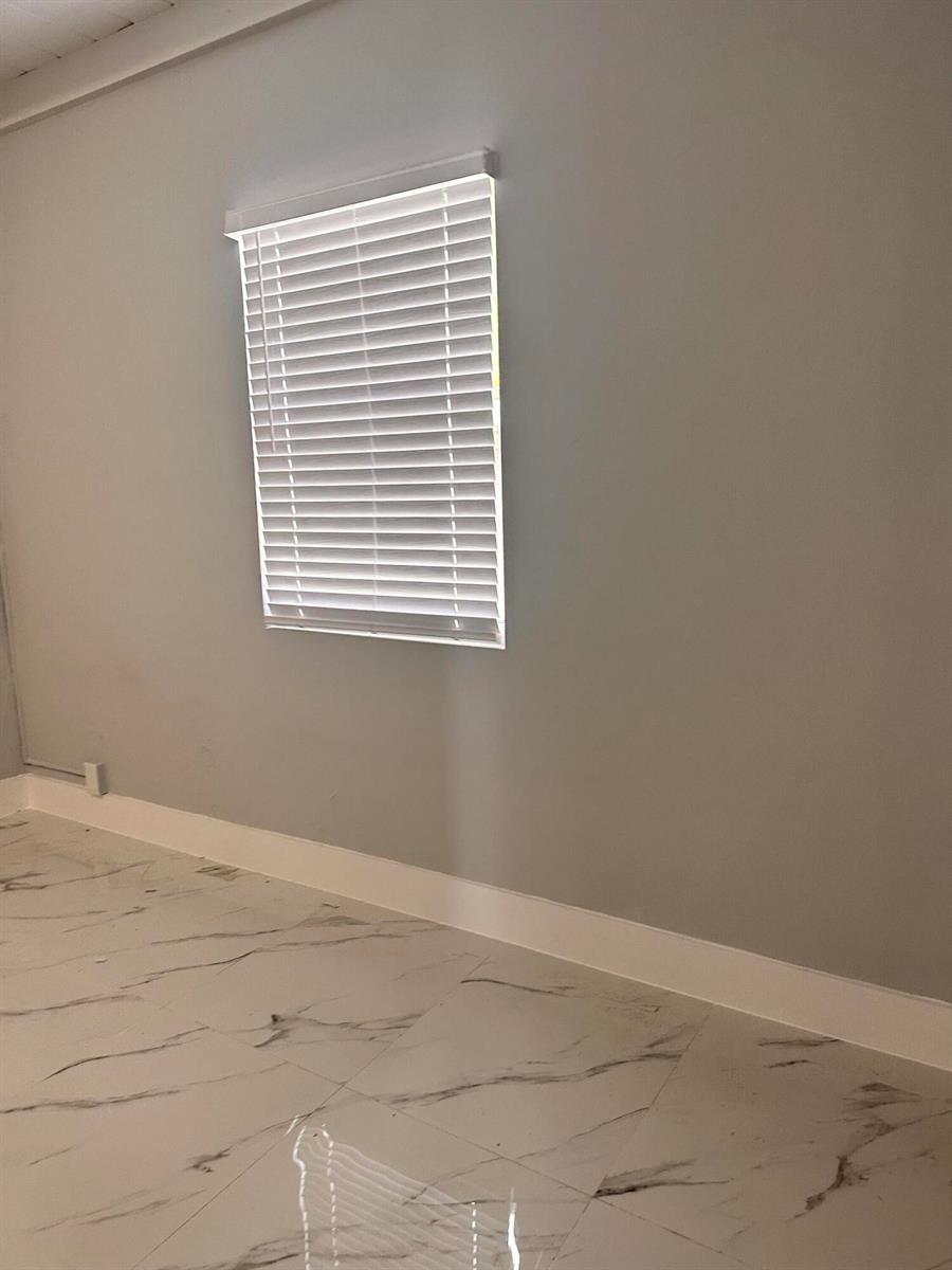 A room with light gray walls, white baseboards, and white marble-patterned tile flooring — 3004 Alice Drive # 1, Palm Springs FL 33461, PALM SPRINGS, FL