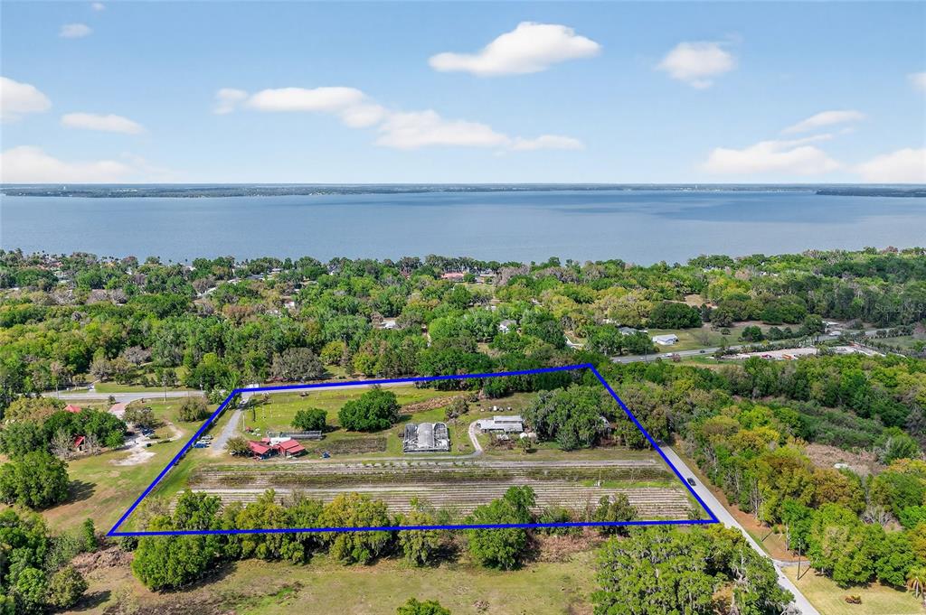 An aerial view shows a rectangular property with a farm, buildings, and surrounding trees — 26921 BLOOMFIELD AVENUE, YALAHA, FL