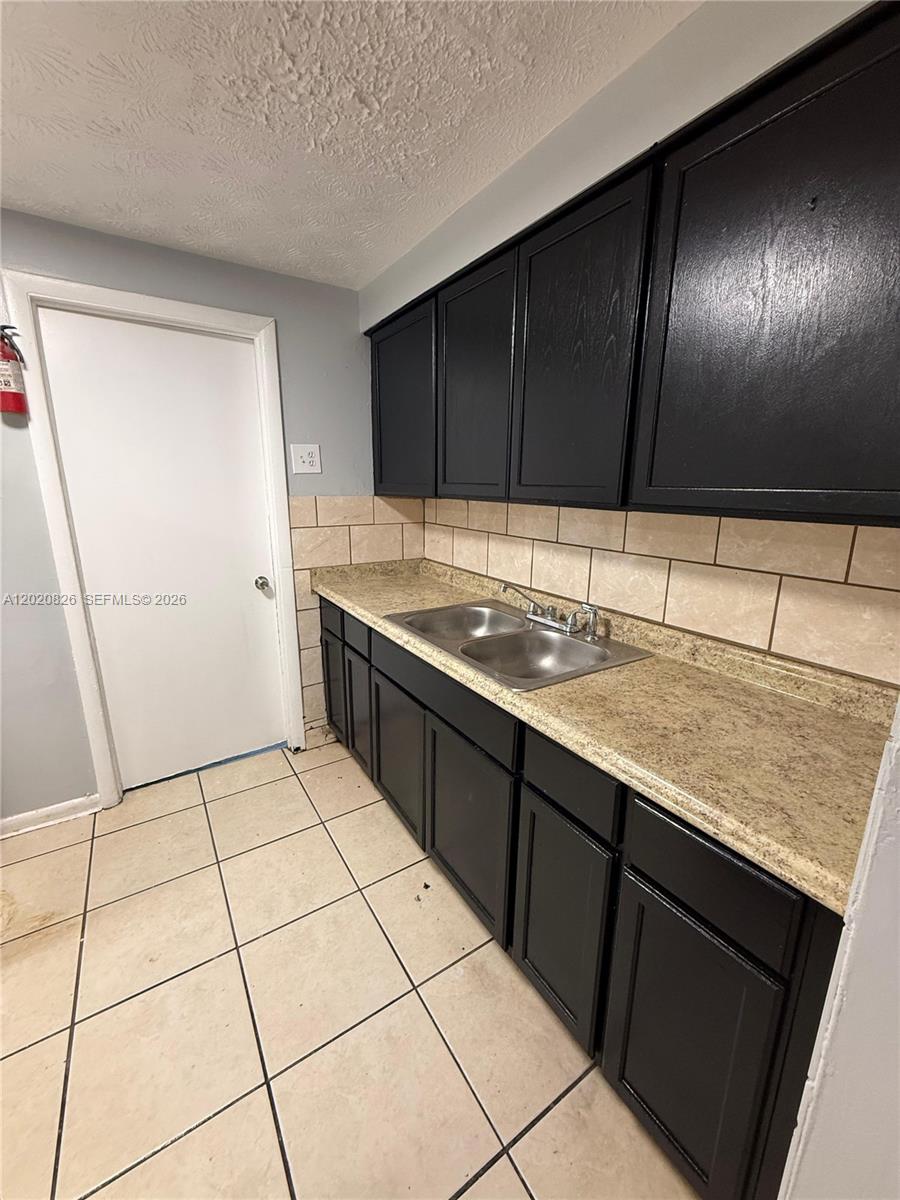 A kitchen features black cabinets, a tan laminate countertop, a double sink, and tiled flooring — 2644 West, Jacksonville FL 32209, JACKSONVILLE, FL