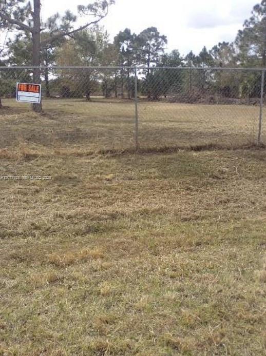 A chain-link fence encloses a vacant, grassy lot with trees in the background — 460 Horse Club Ave, Clewiston FL 33440, CLEWISTON, FL