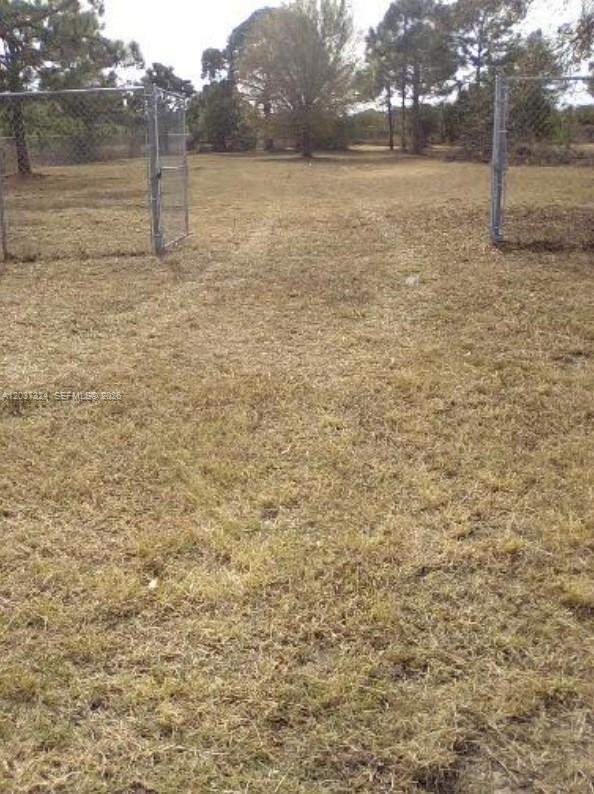 A fenced entrance leads into a large, grassy, open lot with scattered trees — 460 Horse Club Ave, Clewiston FL 33440, CLEWISTON, FL