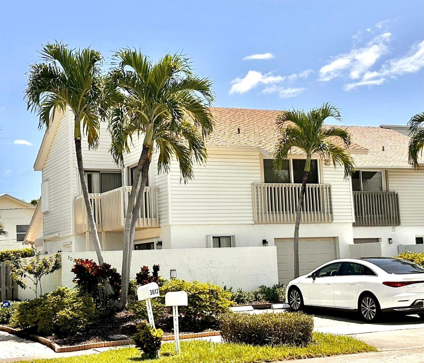 A two-story white townhouse with palm trees, a balcony, and a white car parked outside — 3021 Florida Boulevard, Delray Beach FL 33483, DELRAY BEACH, FL