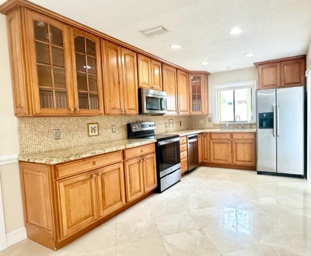 A kitchen features wood cabinets, granite countertops, stainless steel appliances, and light-colored tile flooring — 3021 Florida Boulevard, Delray Beach FL 33483, DELRAY BEACH, FL