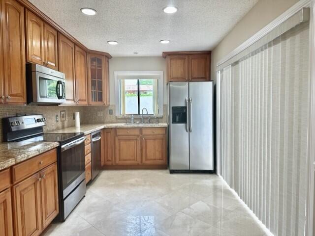 A kitchen features wood cabinets, stainless steel appliances, granite countertops, and tile flooring — 3021 Florida Boulevard, Delray Beach FL 33483, DELRAY BEACH, FL