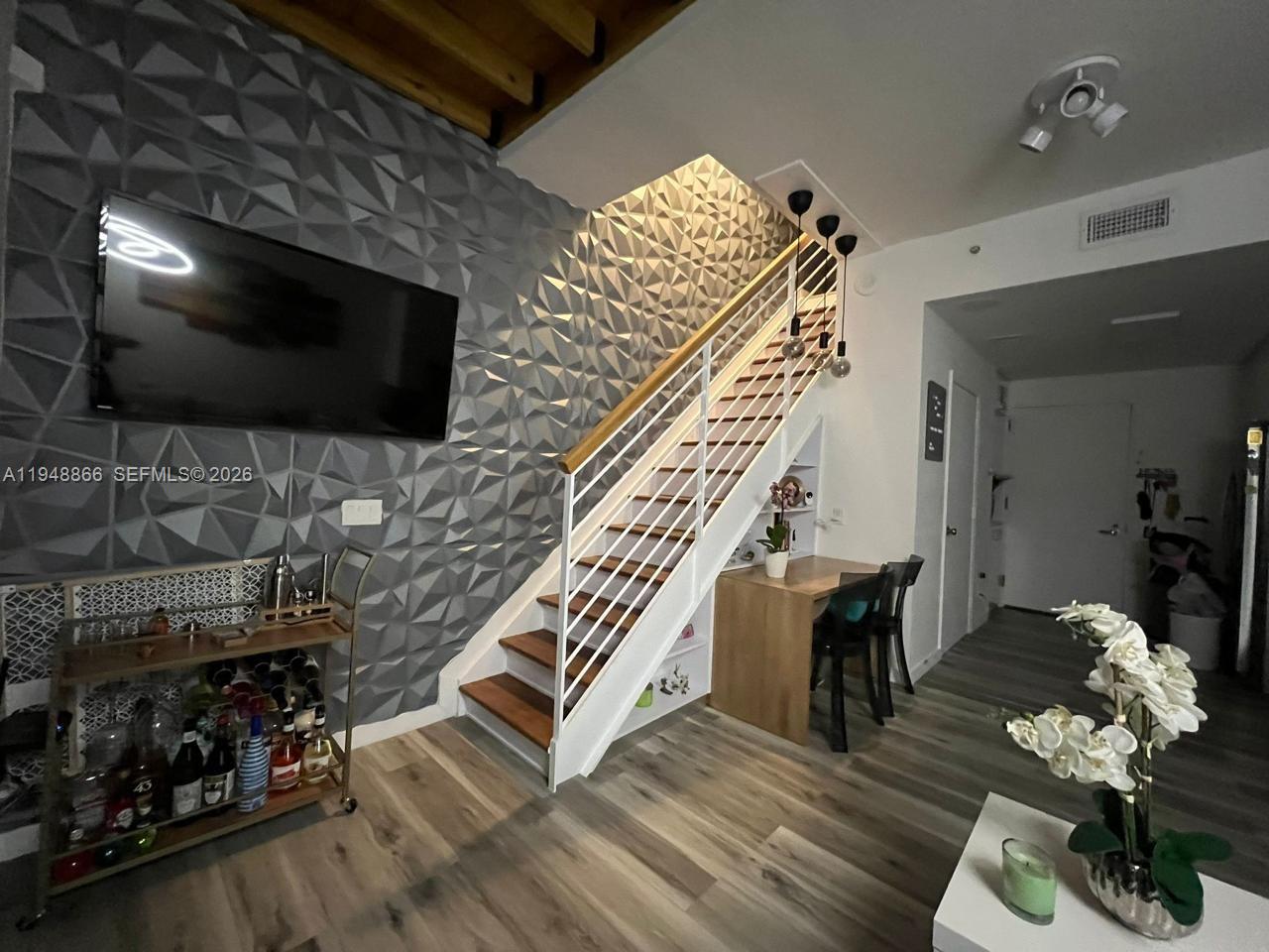 A living area features a textured gray accent wall, a staircase, and a small dining nook — 60 SW 13th St # 3013, Miami FL 33130, MIAMI, FL