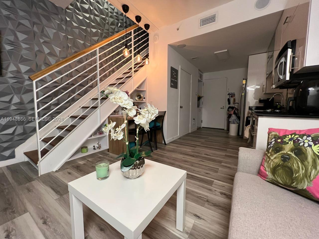 A living room features a staircase with a geometric accent wall and a small kitchen — 60 SW 13th St # 3013, Miami FL 33130, MIAMI, FL