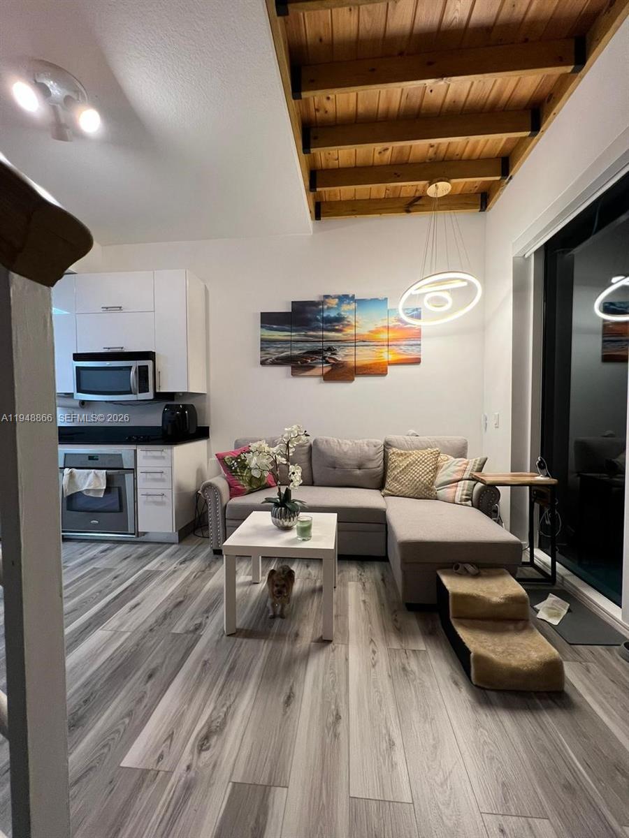 A living room with a sectional sofa, kitchen area, and exposed wood ceiling beams — 60 SW 13th St # 3013, Miami FL 33130, MIAMI, FL