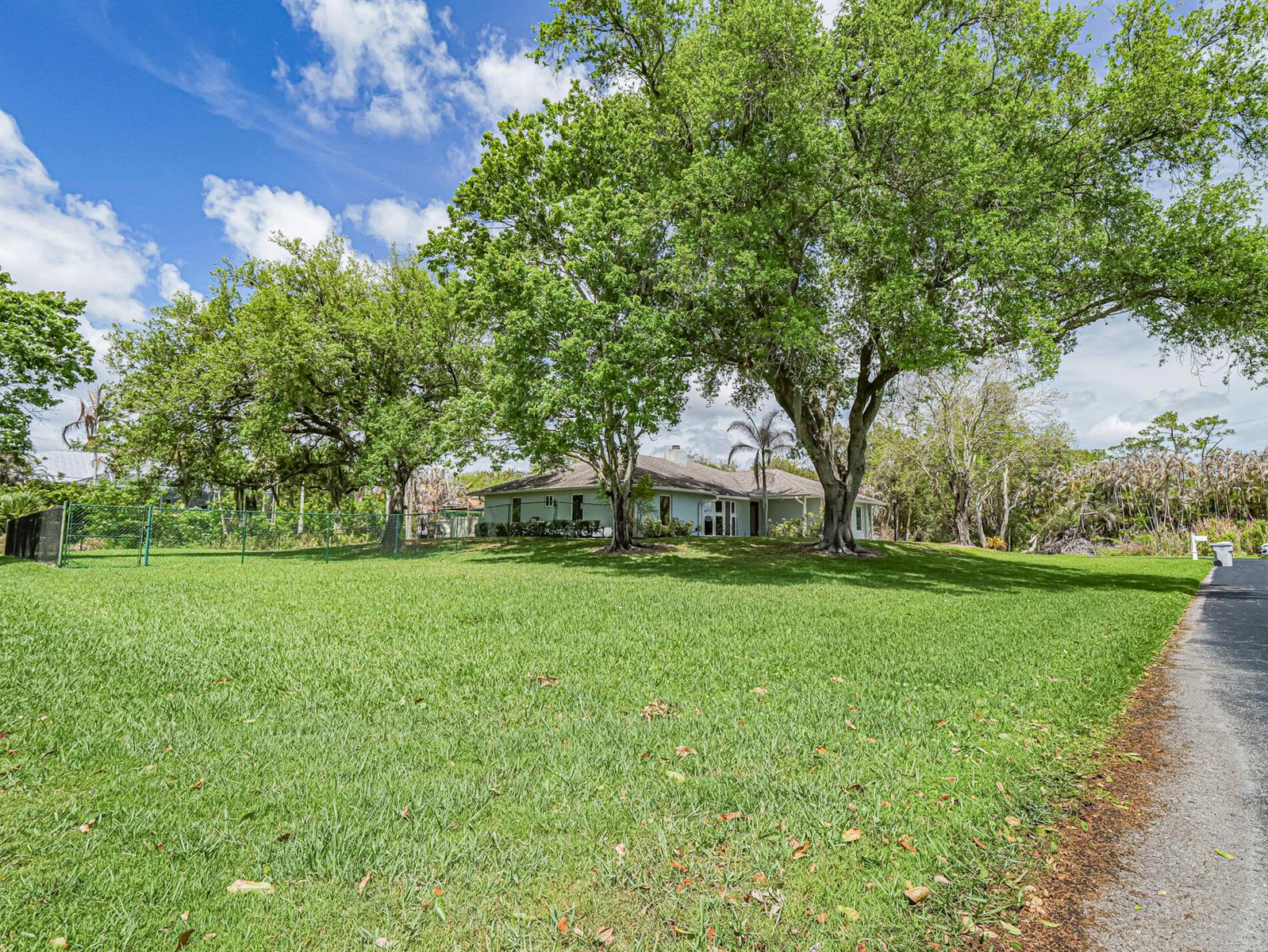 A light green house with a brown garage door, stone accents, and a white gate — 595 45th Court, Vero Beach FL 32968, VERO BEACH, FL