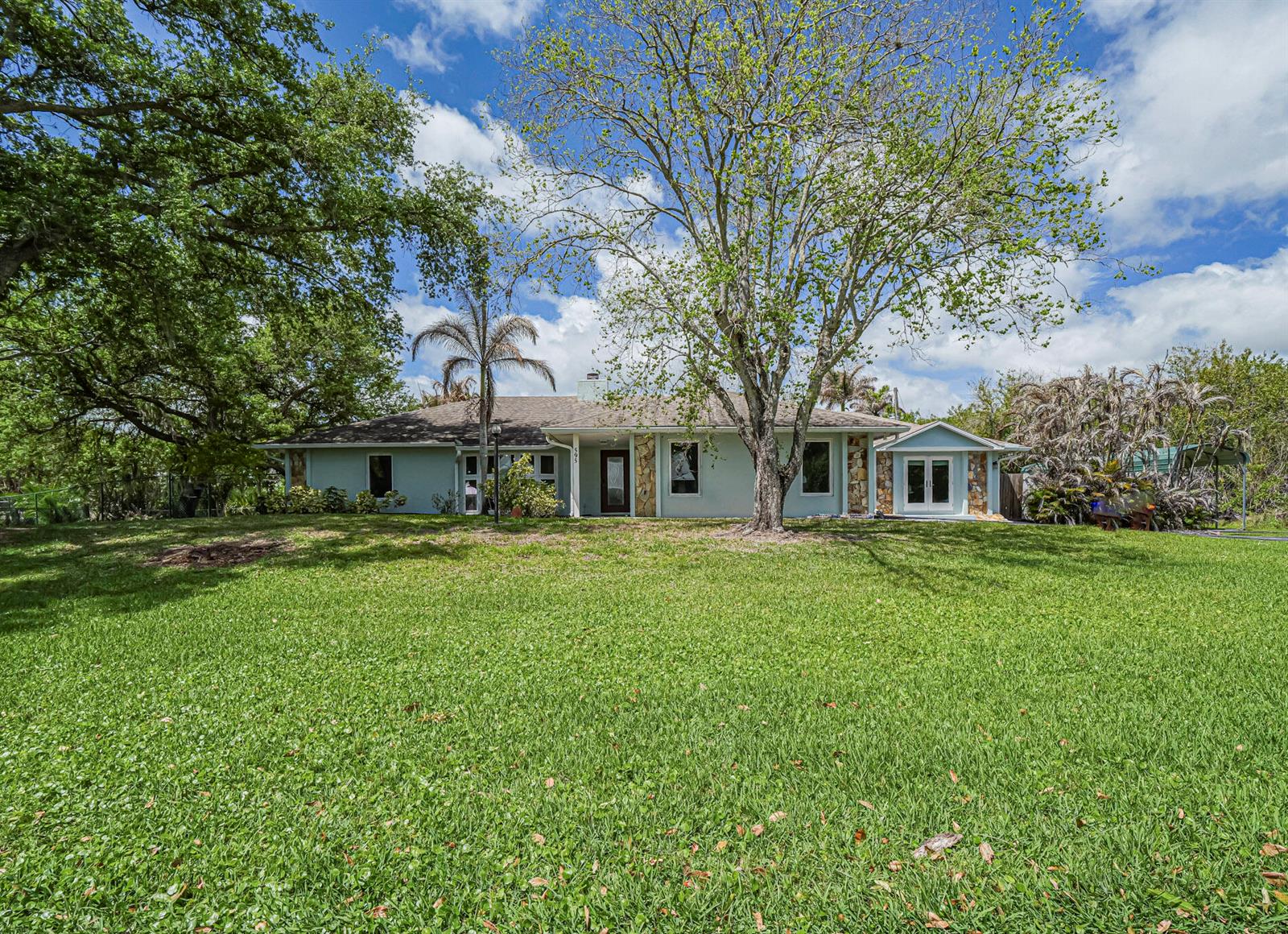 A light green house exterior features a brown front door and a large bay window — 595 45th Court, Vero Beach FL 32968, VERO BEACH, FL