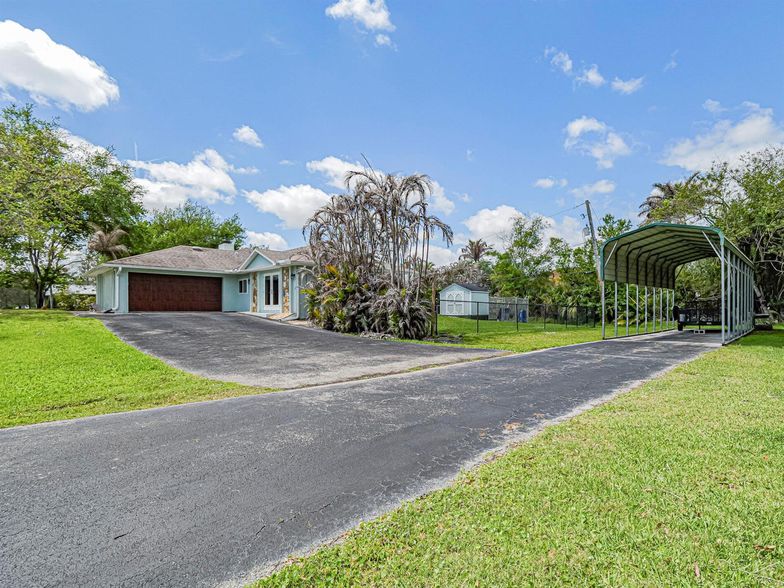 An aerial view shows a single-story house with a driveway, carport, and large front lawn — 595 45th Court, Vero Beach FL 32968, VERO BEACH, FL