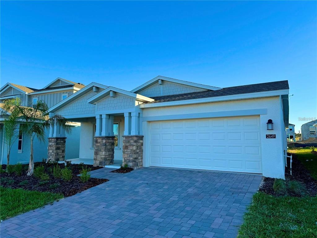 A single-story house with a white stucco facade, stone-accented columns, and a paved driveway — 2649 ARMSTRONG AVENUE UNIT A, CLERMONT, FL