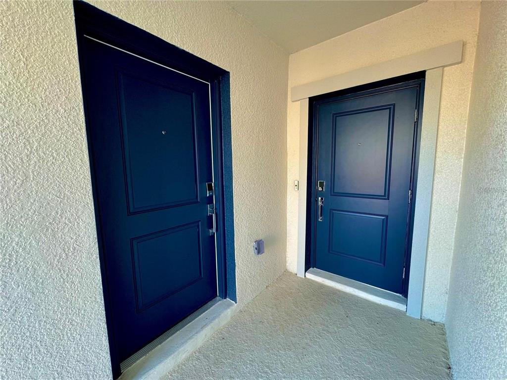 Two dark blue doors with silver hardware are set into a light-colored stucco wall — 2649 ARMSTRONG AVENUE UNIT A, CLERMONT, FL