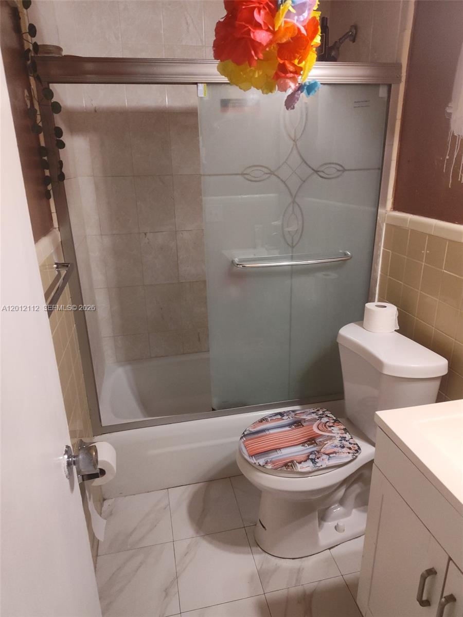 A bathroom features a tiled shower with a sliding glass door and a white toilet — 625 SW 20th Ct # 8A, Delray Beach FL 33445, DELRAY BEACH, FL