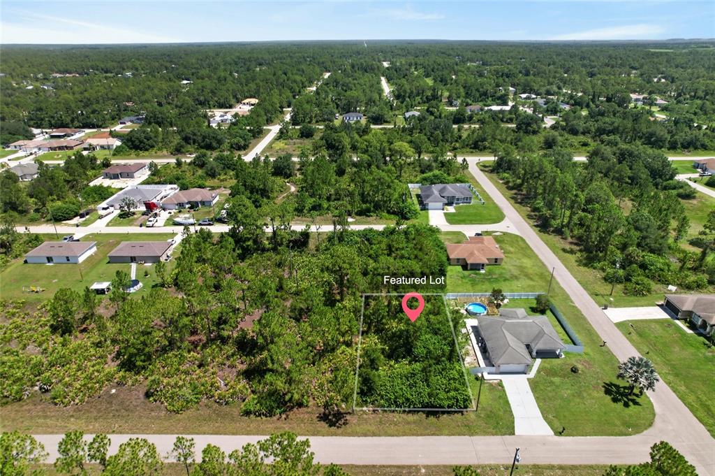 An aerial view shows a vacant, wooded residential lot outlined in a suburban neighborhood — 1141 COVE STREET E, LEHIGH ACRES, FL