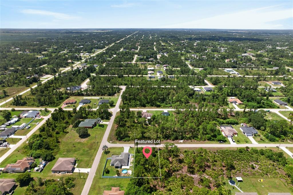 An aerial view shows a vacant, wooded lot marked with a pin in a neighborhood — 1141 COVE STREET E, LEHIGH ACRES, FL