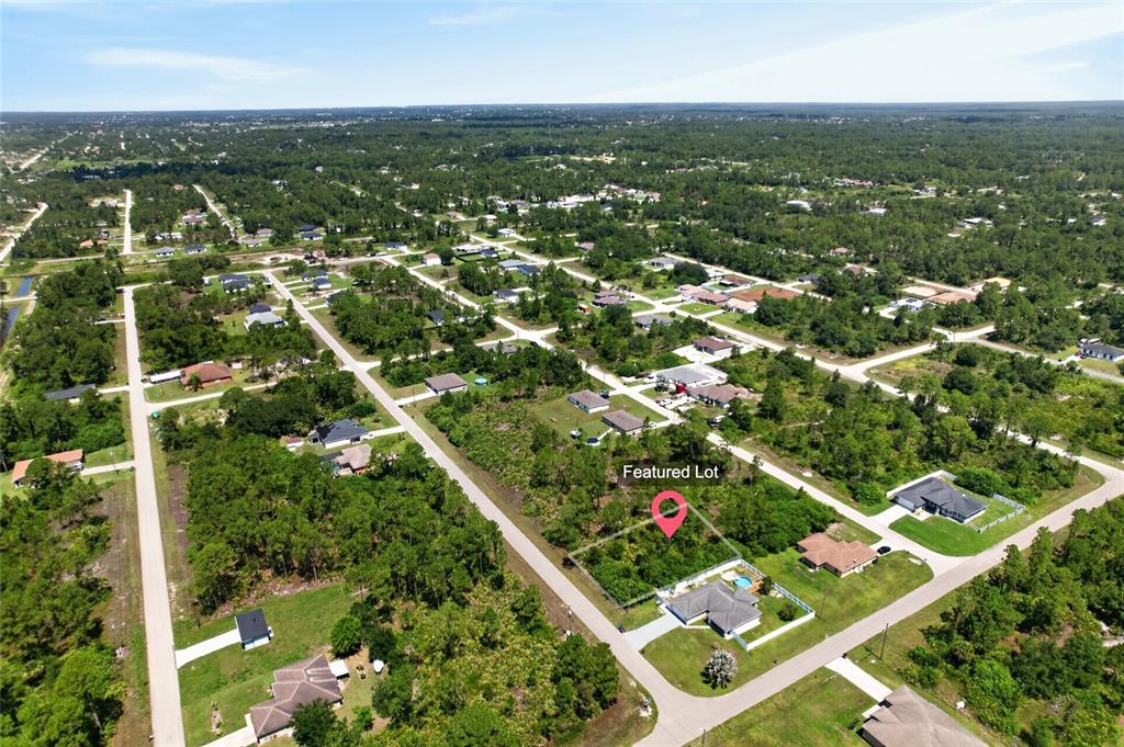 An aerial view shows a vacant, wooded residential lot marked with a red pin — 1141 COVE STREET E, LEHIGH ACRES, FL