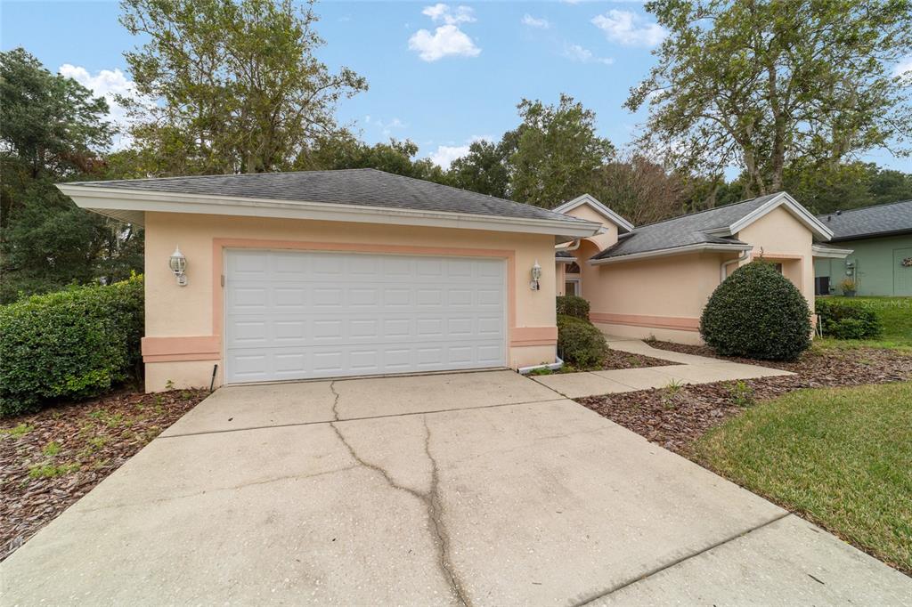 A peach-colored house with a two-car garage and a cracked concrete driveway — 11481 SW 82ND COURT ROAD, OCALA, FL