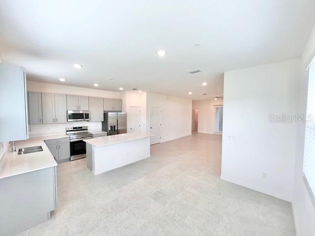 A modern kitchen features light gray cabinetry, stainless steel appliances, and a central island — 1638 ACCLAIM ROAD, APOPKA, FL