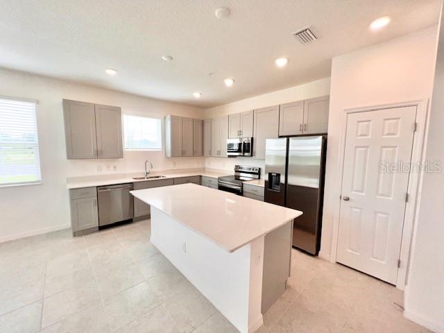 A modern kitchen features light gray cabinets, stainless steel appliances, and a central island — 1638 ACCLAIM ROAD, APOPKA, FL