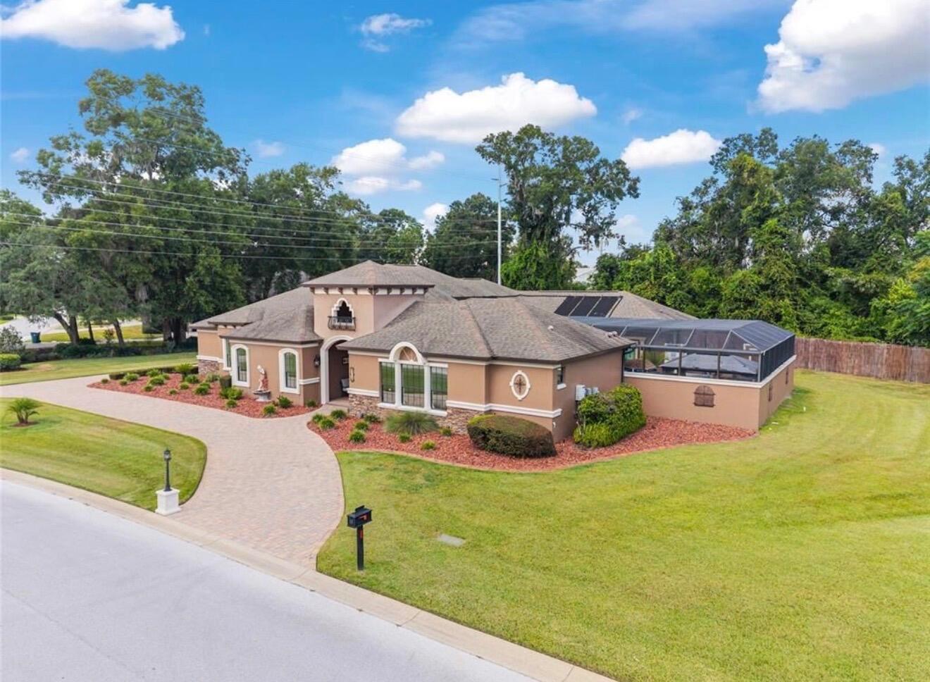 An aerial view of a single-story tan house with a paved driveway and screened pool — 2901 SE 28th Lane, Ocala FL 34471, OCALA, FL