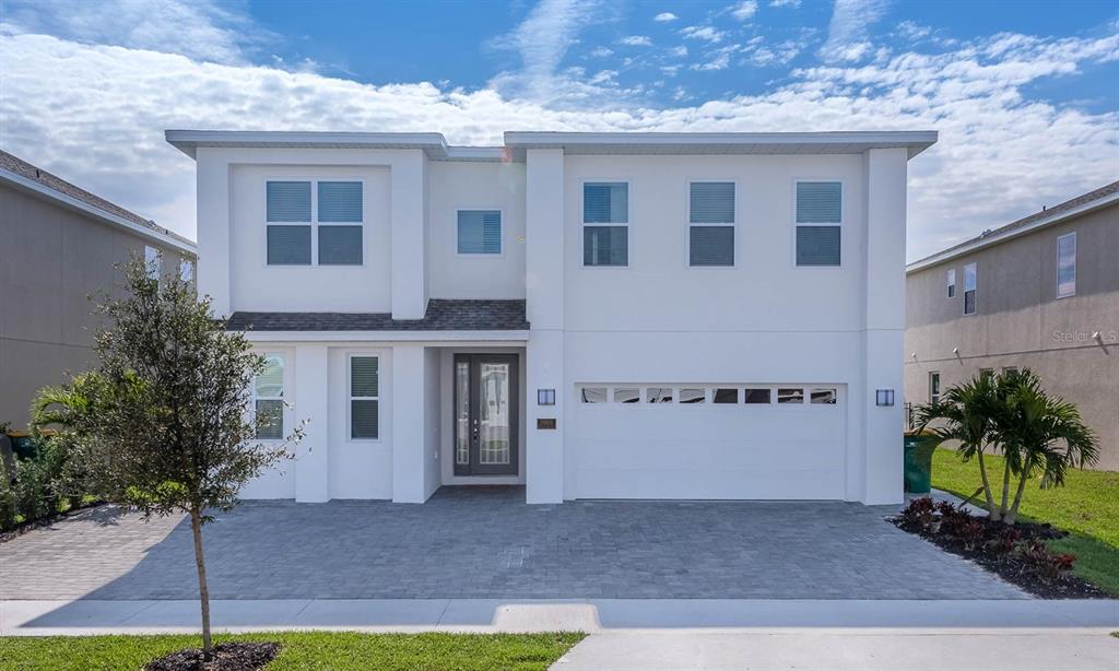 A two-story white house with a paved driveway and a two-car garage — 7602 MACKINAW LANE, KISSIMMEE, FL