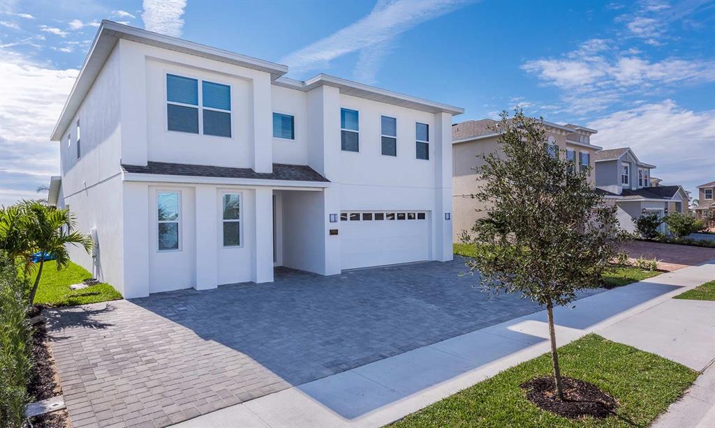 A two-story white house with a paved driveway and a two-car garage — 7602 MACKINAW LANE, KISSIMMEE, FL