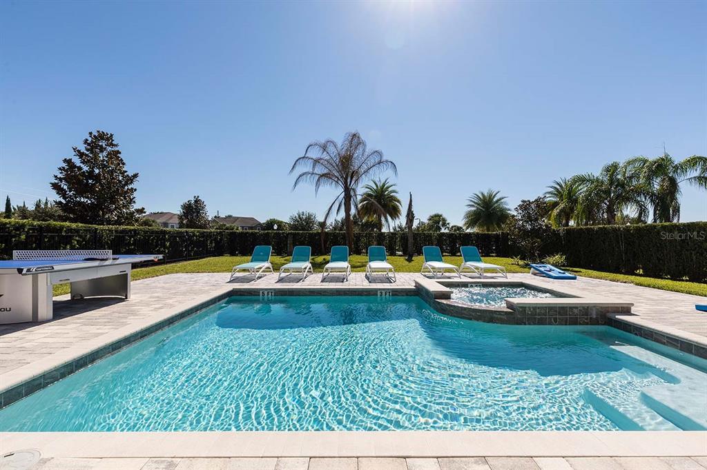 A swimming pool with a hot tub and lounge chairs on a paved patio — 7602 MACKINAW LANE, KISSIMMEE, FL
