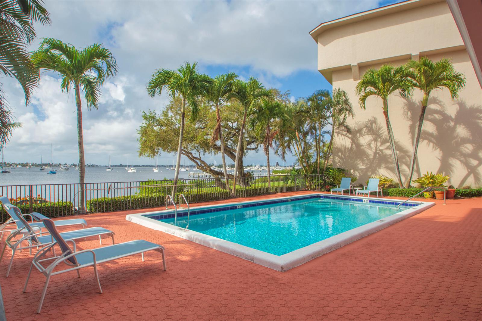 A swimming pool sits on a red patio overlooking a bay with moored boats — 624 SW St. Lucie Crescent # 206, Stuart FL 34994, STUART, FL