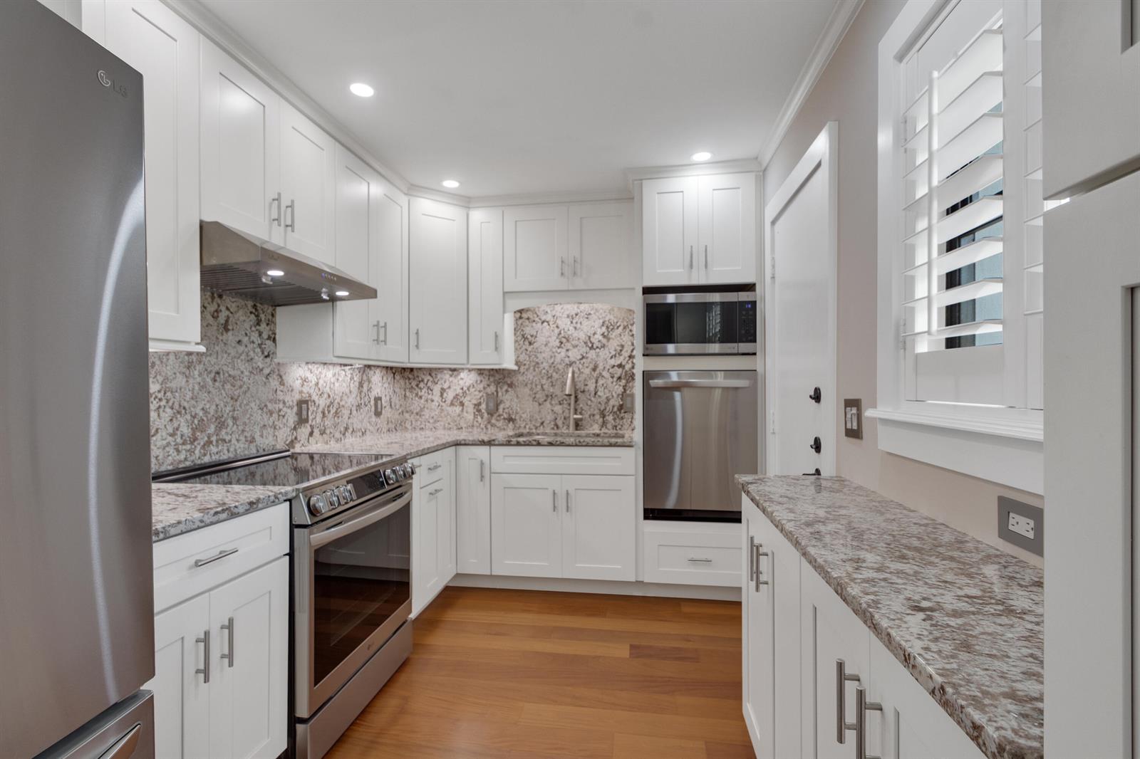 A kitchen with white cabinets, stainless steel appliances, and granite countertops over hardwood floors — 624 SW St. Lucie Crescent # 206, Stuart FL 34994, STUART, FL