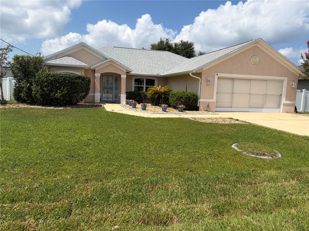 A single-story house with a beige stucco exterior, a gray shingled roof, and a two-car garage — 25 BISCAY LANE, PALM COAST, FL