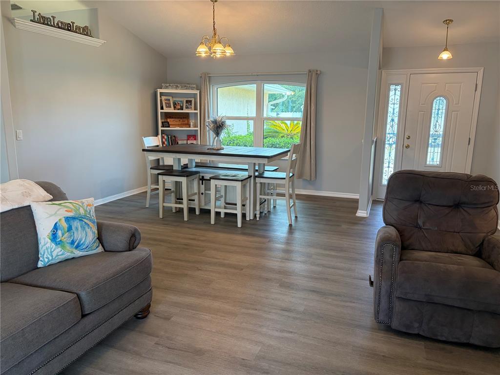 A dining area with a wooden table and stools sits in an open-concept living space — 25 BISCAY LANE, PALM COAST, FL