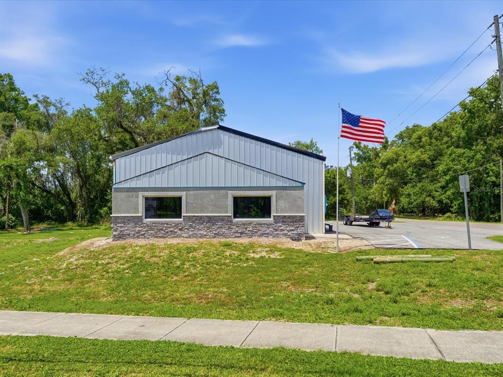 A single-story metal building with stone veneer siding and two windows sits near a road — 490 SMITH STREET, BROOKSVILLE, FL