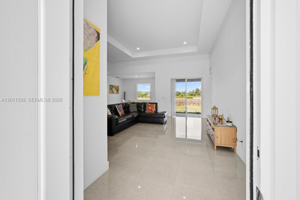 A view from a doorway into a living room with white tile floors and furniture — 1211 Eclat St E, Lehigh Acres FL 33974, LEHIGH ACRES, FL