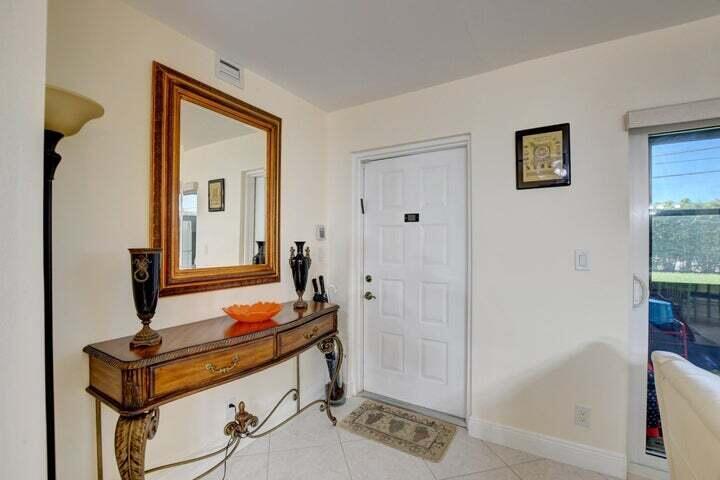 An entryway features a wooden console table, a large mirror, and a white front door — 7539 S Oriole Boulevard # 103, Delray Beach FL 33446, DELRAY BEACH, FL