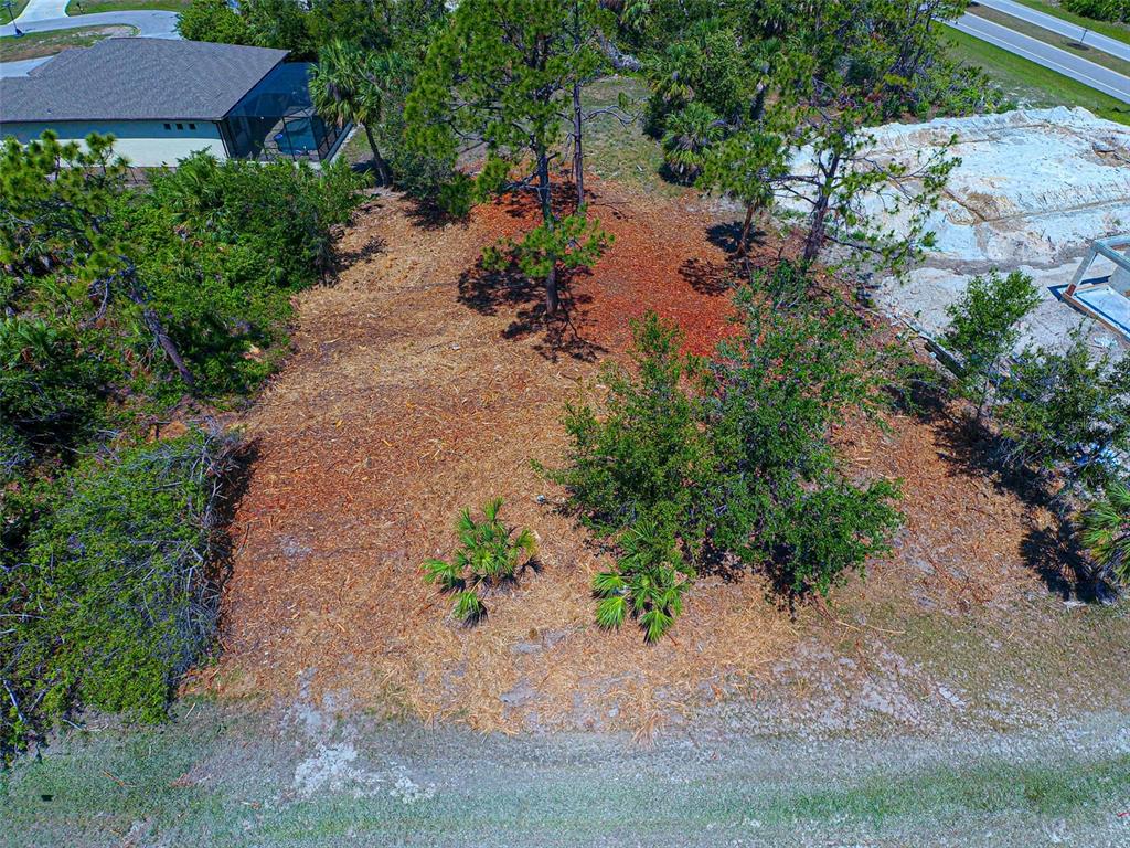 An aerial view shows a cleared, wooded residential lot adjacent to a house and construction site — 116 REDWOOD ROAD, ROTONDA WEST, FL