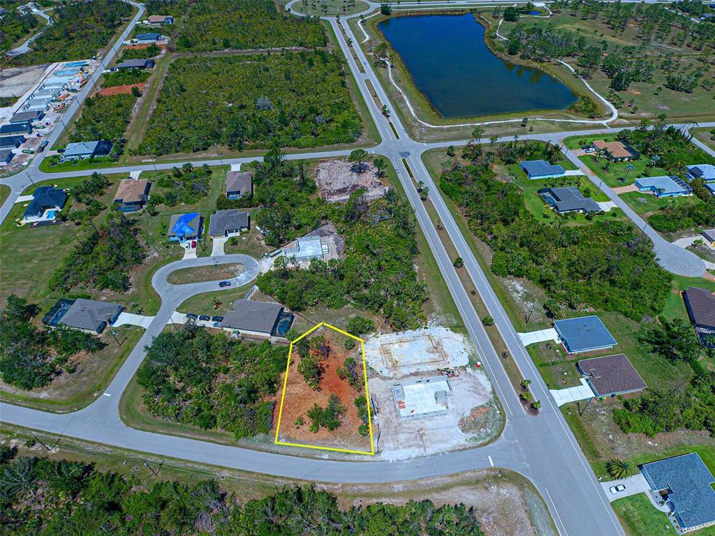 An aerial view shows a vacant residential lot outlined in yellow next to a construction site — 116 REDWOOD ROAD, ROTONDA WEST, FL