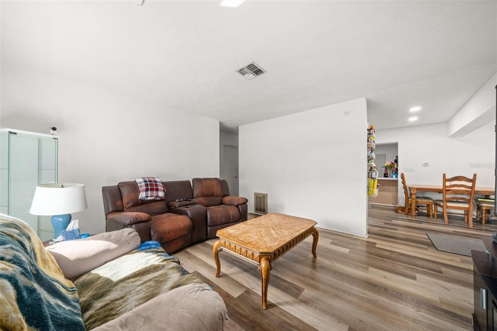 A living room with wood-look flooring, a brown leather sofa, and a coffee table — 1018 BELLEVUE AVENUE, SEBRING, FL