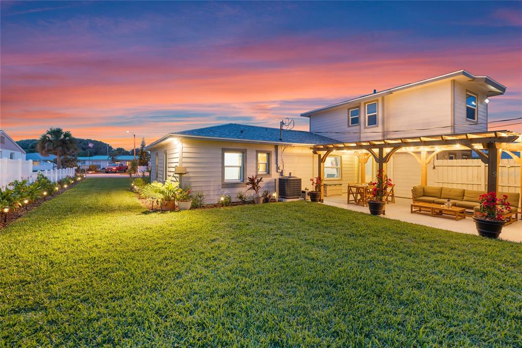 A two-story house exterior features a backyard lawn, a patio, and a wooden pergola — 1409 SOUTHARD AVENUE, NEW SMYRNA BEACH, FL