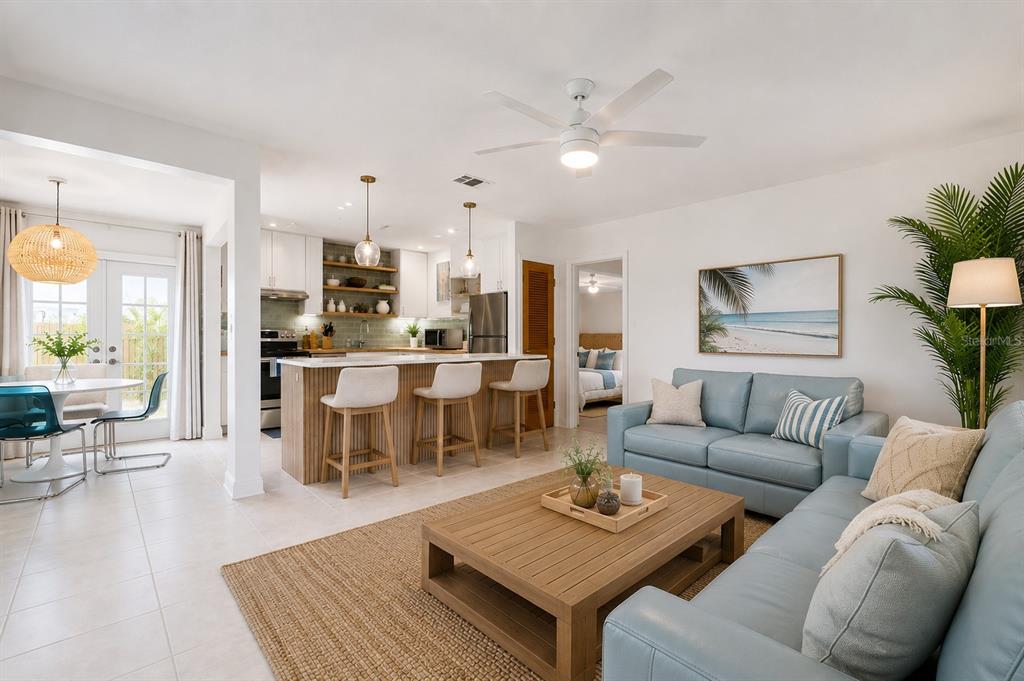 An open-concept living room and kitchen featuring a light blue sofa, wooden coffee table, and island — 1409 SOUTHARD AVENUE, NEW SMYRNA BEACH, FL