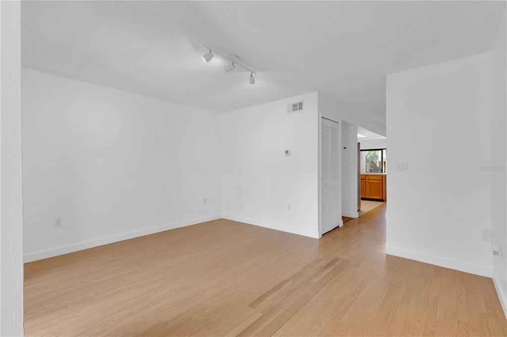 An empty room with white walls, light wood flooring, and a track lighting fixture — 1329 WINDSOR DRIVE, KISSIMMEE, FL
