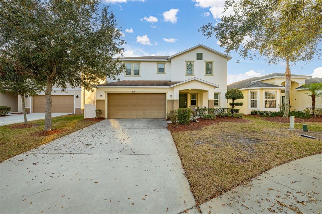 A two-story suburban house with a tan garage, white siding, and a concrete driveway — 947 EMERALD GREEN COURT, KISSIMMEE, FL