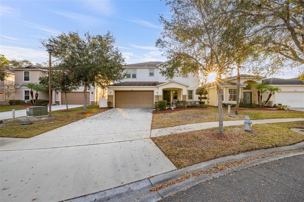 A two-story suburban house with a tan exterior, a two-car garage, and a concrete driveway — 947 EMERALD GREEN COURT, KISSIMMEE, FL