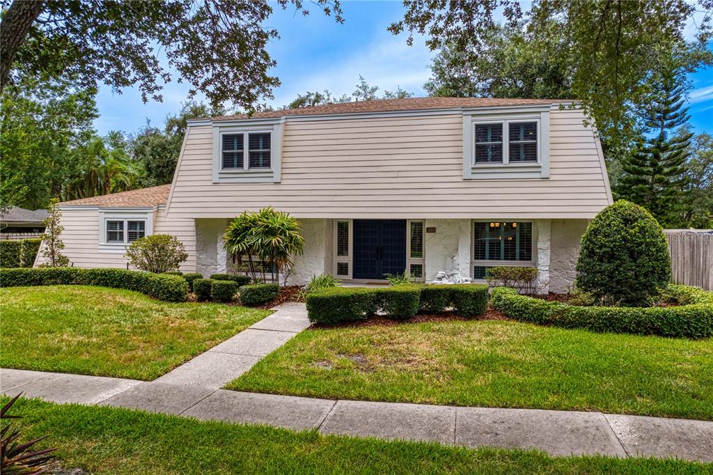 A two-story house with light-colored horizontal siding, a stone facade, and a manicured lawn — 13305 GOLF CREST CIRCLE, TAMPA, FL