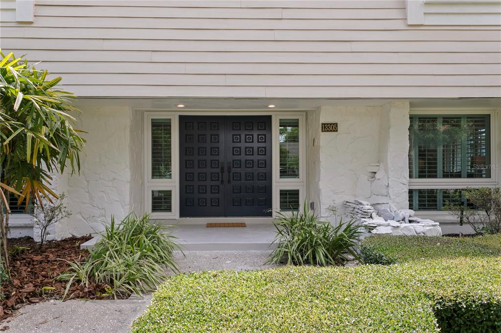 A front entrance features a dark double door with square panels and white stone siding — 13305 GOLF CREST CIRCLE, TAMPA, FL