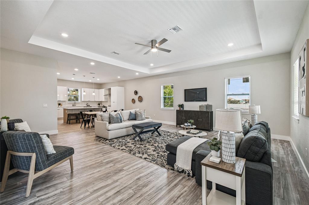 An open-concept living room and kitchen featuring wood-look flooring and a tray ceiling — 4559 MITCHER ROAD, NEW PORT RICHEY, FL