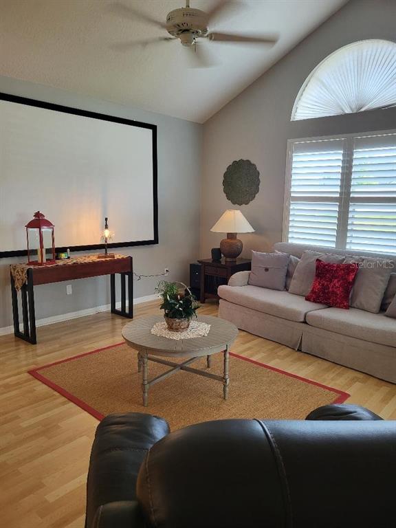 A living room features a large projector screen, light wood flooring, and a beige sofa — 3709 MOLLIE LANE, RUSKIN, FL