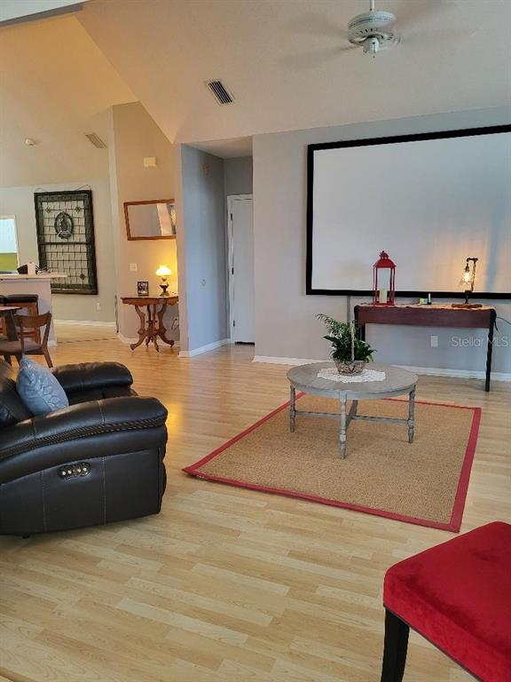 A living room features light wood flooring, a projector screen, and a round coffee table — 3709 MOLLIE LANE, RUSKIN, FL