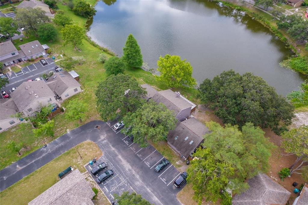 An aerial view shows a residential building with a parking lot next to a lake — 4817 LIGHTHOUSE CIRCLE UNIT 58, ORLANDO, FL