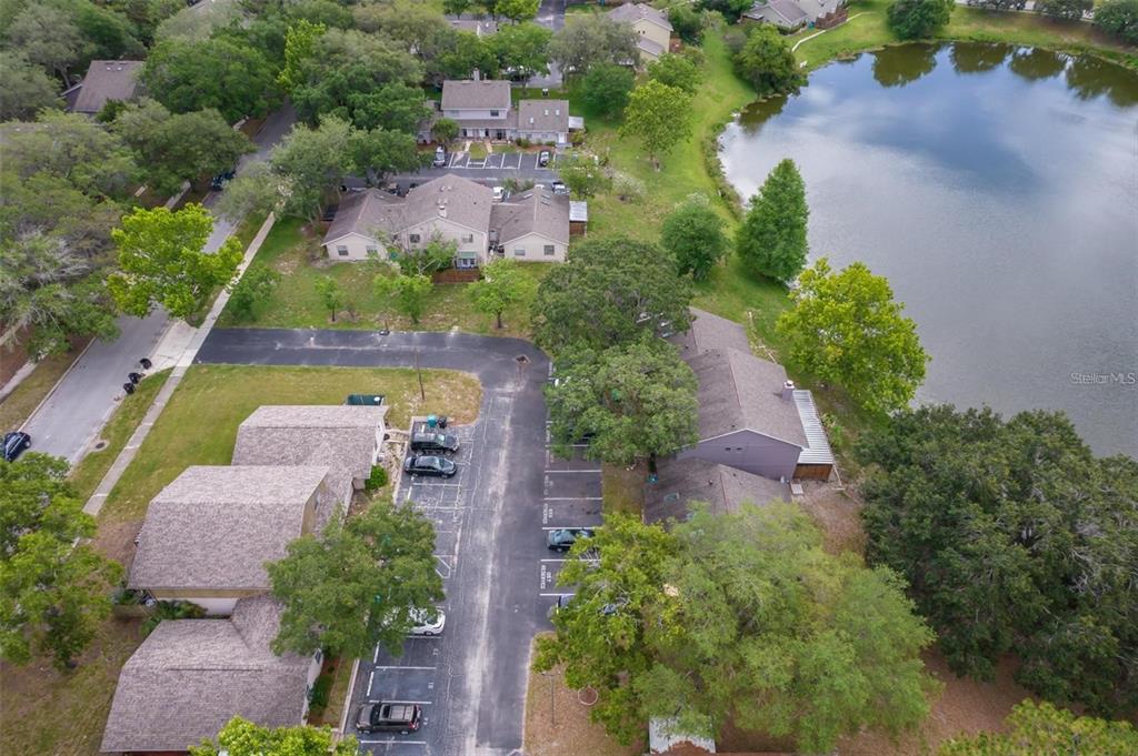 An aerial view shows multi-family residential buildings, a parking lot, and a lake — 4817 LIGHTHOUSE CIRCLE UNIT 58, ORLANDO, FL